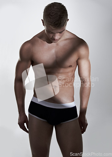 Image of Man, underwear and bodybuilder in studio for fitness, wellness and abs in shadow by white background. Person, model and exercise for healthy body with thinking, strong or development for aesthetic