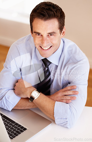 Image of Portrait of businessman at desk with smile, laptop and confidence for market research at startup. Office, computer and face of happy man at digital agency with pride, online trading and networking.