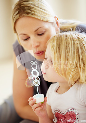 Image of Blowing, bubbles and games with mom and child together in home playing with toys for fun. Playful, mother and daughter with liquid, soap and bonding on holiday, vacation or relax on weekend with love