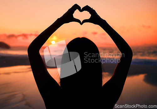 Image of Woman, silhouette and sunset at beach with heart hands for love, care and kindness with sign, summer and dusk. Girl, person and ocean with symbol, emoji or icon on vacation, nature or outdoor in dark