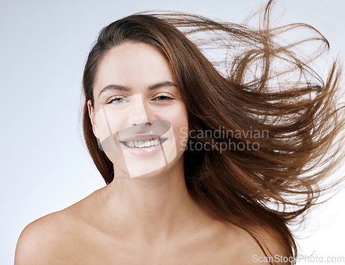 Image of Hair care, woman or portrait and happy in studio with breeze, collagen treatment or brazilian for shine. Person, smile or cosmetics and dermatology, keratin or beauty on white background for wellness