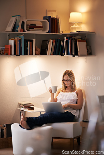 Image of Woman, laptop and reading with coffee at night on chair in relax or living room at home. Female person, journalist or bookworm sitting with cup of tea and computer for online connection at house