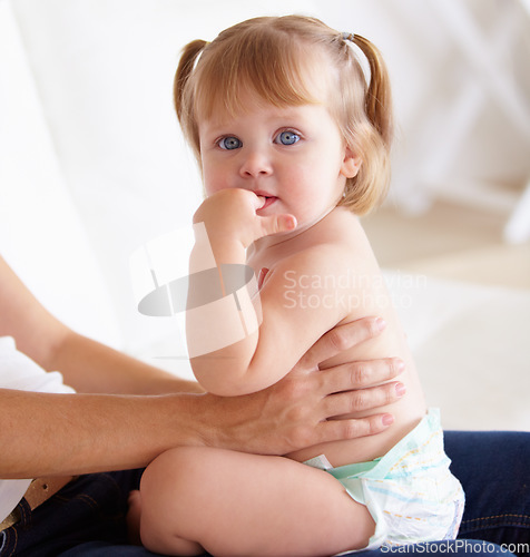 Image of Portrait, family and a girl baby on the lap of a parent closeup on the floor of a living room in their home. Kids, growth and child development with hands holding a cute young toddler in a diaper