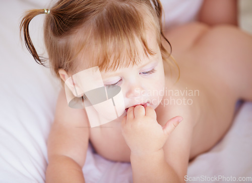 Image of Face, growth and child development with a baby in the bedroom to relax alone in the morning. Home, kids or youth and an adorable young infant girl on a bed with blankets for comfort in an apartment