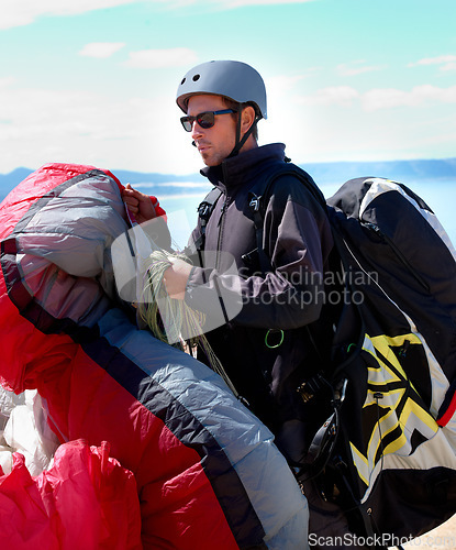 Image of Paragliding, parachute or man in nature for sport, preparation or helmet to exercise for health support. Athlete, training or fitness for outdoor wellness, backpack or safety equipment in countryside