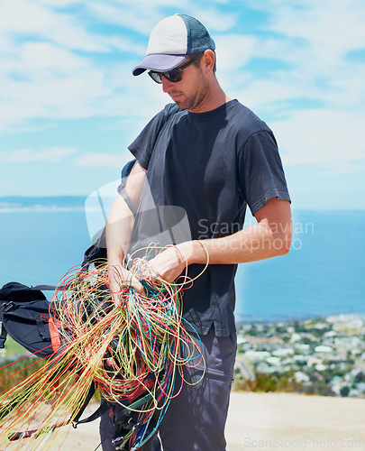 Image of Man, parachute or safety in nature for sport, preparation or harness to exercise for health. Athlete, extreme sports or strings for fitness with outdoor wellness, equipment and gear for paragliding