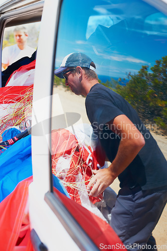 Image of Extreme sports, adventure and a parachute in a car with a man unpacking equipment for an adrenaline activity. Travel, skydiving and getting ready for a jump outdoor in the dessert for an experience