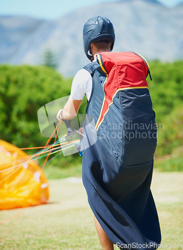 Image of Nature, man and parachute with ground for sport preparation, strings and training for paragliding exercise. Person, safety gear and helmet for outdoor fitness with toggle, fearless and countryside