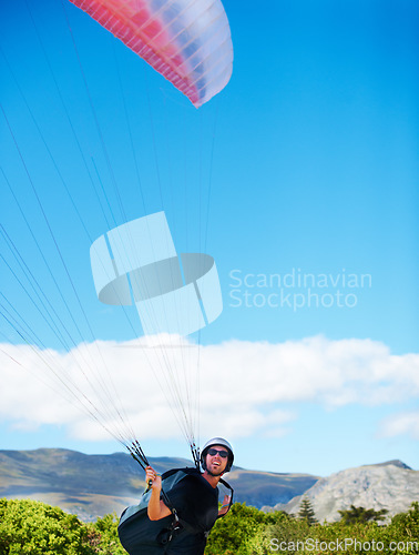 Image of Man, parachute or paragliding sport in preparation exercise, healthy adventure or extreme fitness. Person, launch or fearless for outdoor flight in health wellness, helmet or safety gear by blue sky