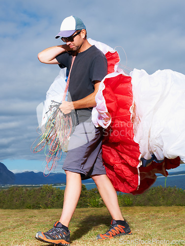 Image of Equipment, parachute or man in nature for sport, smile or strings for exercise for health support. Person, walk or preparation in outdoor fitness for wellness, fearless or safety gear in countryside