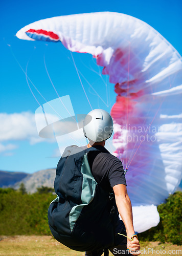 Image of Man, parachute and launch sport with courage, healthy adventure and paragliding for extreme fitness. Person, preparation and fearless in forest for flight take off with helmet and safety gear in wind