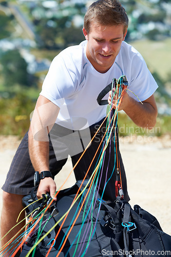 Image of Man, safety harness or paragliding sport in launch in training, healthy adventure or extreme fitness. Person, preparation and fearless outdoor for flight with smile and parachute gear in countryside