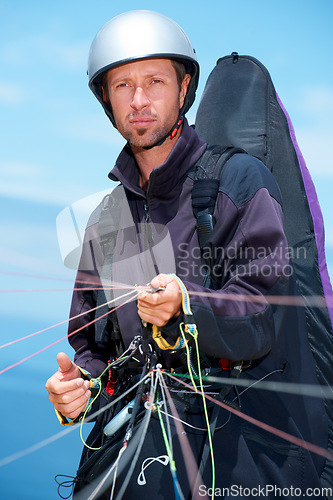 Image of Paragliding, parachute and man with preparation in nature, strings and exercise for health support. Athlete, training or fitness for outdoor with safety harness, helmet or equipment in countryside