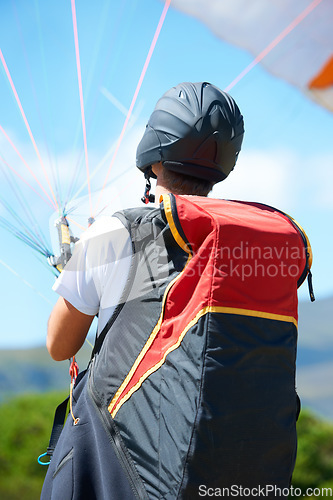 Image of Man, parachute or paragliding launch in nature, exercise or healthy adventure for extreme sport. Person, strings or training for outdoor fitness for wellness, helmet or safety gear by blue sky