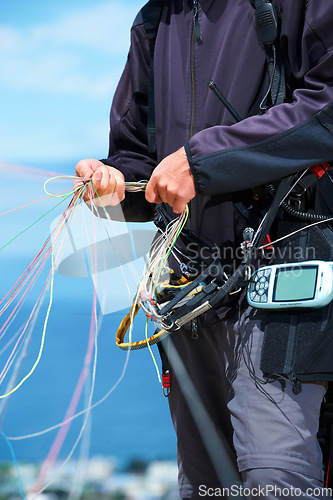 Image of Paragliding, rope and sport with hands of person in nature for flight, travel or vacation. Safety gear, holiday and trip with closeup of man and strings in outdoors for action, parasailing and cord