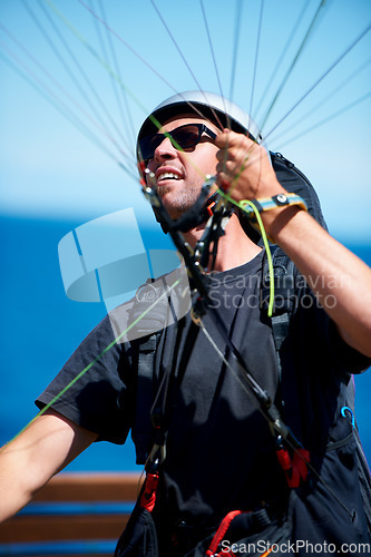 Image of Man, parachute and paragliding launch in air in nature, exercise and healthy adventure fof extreme sport. Person, glide or fearless in outdoor fitness for wellness, helmet or safety gear by blue sky