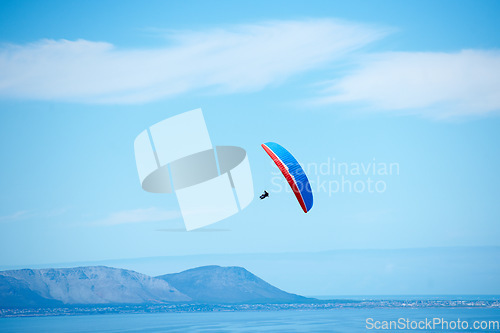 Image of Pilot, parachute and paragliding in blue sky for flight, freedom and courage with extreme sport. Athlete, glide and fearless in outdoor fitness for adventure, health and sports by ocean with mountain