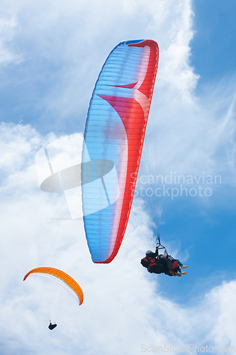 Image of Person, parachute and paragliding in blue sky for flight, stunt and courage with extreme sport. Athlete, glide and fearless in outdoor fitness for adventure, health and sports by ocean with mountain