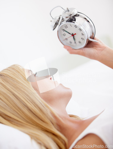 Image of Woman, holding and alarm clock for wake up in bedroom for early, morning and sleep in house. Female person, looking and time with upset, serious and expression for day with noise, alert and sound