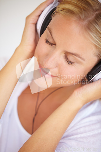 Image of Woman, eyes closed and smile with headphones in closeup for music, podcast or radio. Person, calm or peaceful expression on face for listening, audio or song in home streaming service on internet