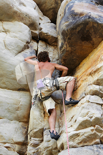 Image of Man, rope and rock climbing up mountain for adventure exercise, cardio or peak reaching. Male person, safety gear and brave explore or outdoor practice as trekking hiker, danger challenge or training