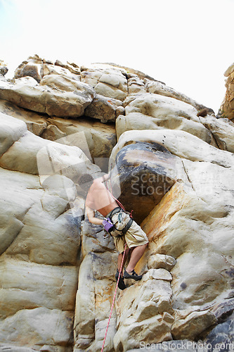 Image of Man, mountain and rock climbing or chalk for grip as outdoor performance, adventure or gear. Male person, hanging and rope on cliff or fearless danger on boulder stone, training for exercise discover