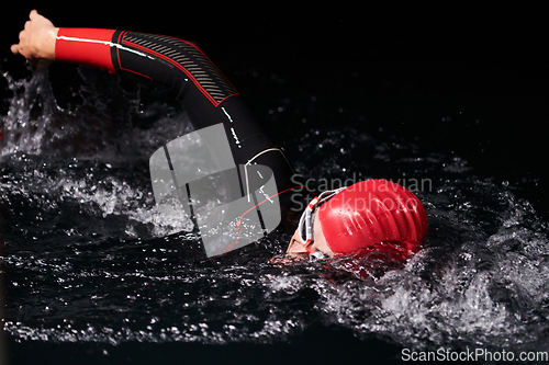 Image of authentic triathlete swimmer having a break during hard training on night neon gel light