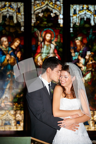 Image of Happy couple, hug and kiss at wedding in church for marriage love or vow in commitment together. Married man or groom hugging woman or bride smile for embrace, loyalty or support in trust at ceremony