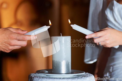 Image of Couple, hands and candle at wedding for love, unity and commitment at church or ceremony with closeup. Marriage, man and woman with light for trust, relationship and compromise with bride and groom