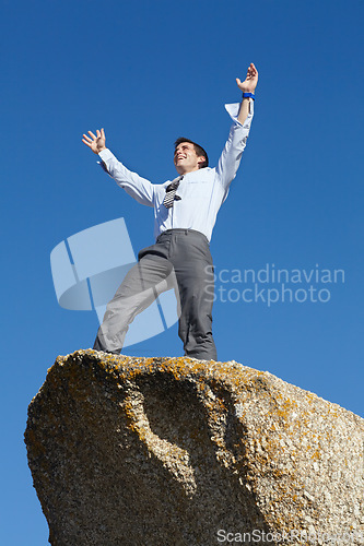 Image of Businessman, success and freedom on cliff with sky, rock and peak of mountain in nature. Happy, person and celebration of winning an achievement, challenge or climbing in business and career progress