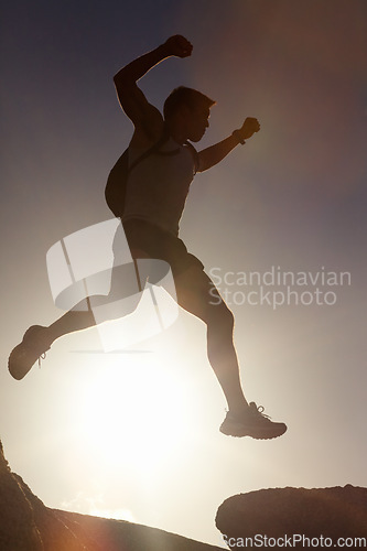 Image of Man, silhouette and jump on rock at sunset with freedom, adventure and challenge on mountain or cliff. Climbing, hill and person with fearless leap in exercise, sport or energy at with sky in summer