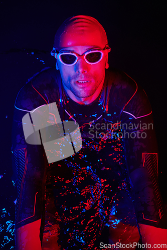 Image of authentic triathlete swimmer having a break during hard training on night neon gel light