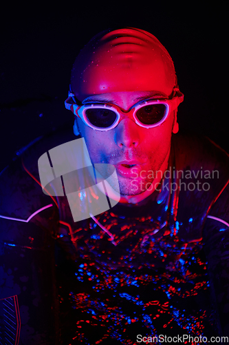 Image of authentic triathlete swimmer having a break during hard training on night neon gel light