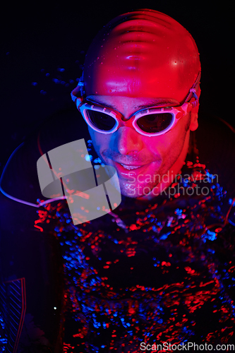 Image of authentic triathlete swimmer having a break during hard training on night neon gel light