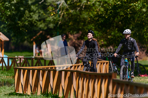 Image of A blissful couple, adorned in professional cycling gear, enjoys a romantic bicycle ride through a park, surrounded by modern natural attractions, radiating love and happiness