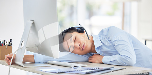 Image of Call center, businessman and sleeping on desk and tired while being overworked and exhausted. Nap, rest and contact us overtime with a male person or agent sleep in customer service job