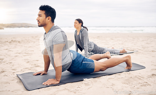 Image of Exercise, yoga and wellness with a couple on the beach for a mental health or awareness workout in the morning. Fitness, pilates or mindfulness with a young man and woman by the ocean or sea for zen