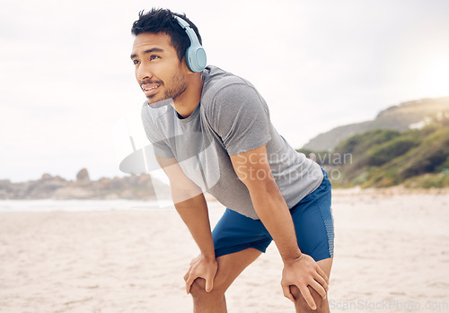 Image of Fitness, headphones and portrait of man on beach running for race, marathon or competition training. Sports, workout and young male athlete listen to music, radio or playlist for exercise by ocean.