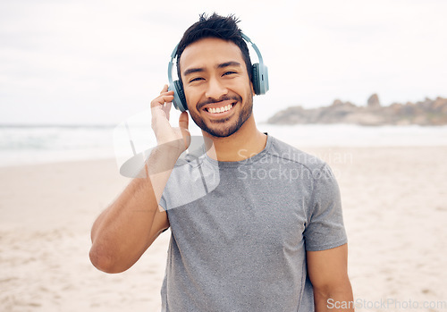 Image of Smile, headphones and portrait of man on the beach running for race, marathon or competition training. Happy, fitness and young male athlete listen to music, radio or playlist for exercise by ocean.