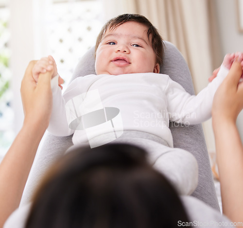 Image of Mother, baby and bedroom with love and care or security holding hands for bond or comfort and peace. A woman or mom and infant child on legs for safety in a family home with growth and connection