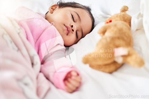 Image of Baby, girl and sleeping in bed with teddy bear, animal and peace in home with blanket and comfort. Child, rest and sleep in morning, nap and routine for health, wellness and calm face of infant