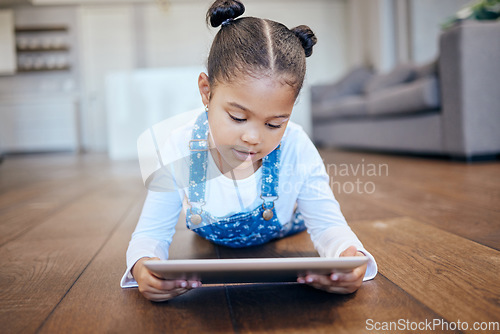 Image of Kid, little girl and tablet for streaming in home with internet for entertainment, learning or watching. Child, youth and lying on floor in living room with technology for online, cartoon or game