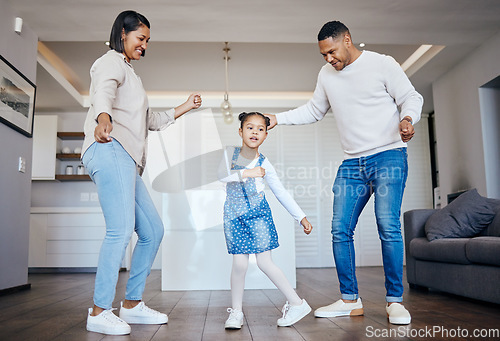 Image of Dance, love and freedom with an interracial family having fun in the living room of their home together. Energy, smile or happy with a mother, father and excited daughter moving in their apartment