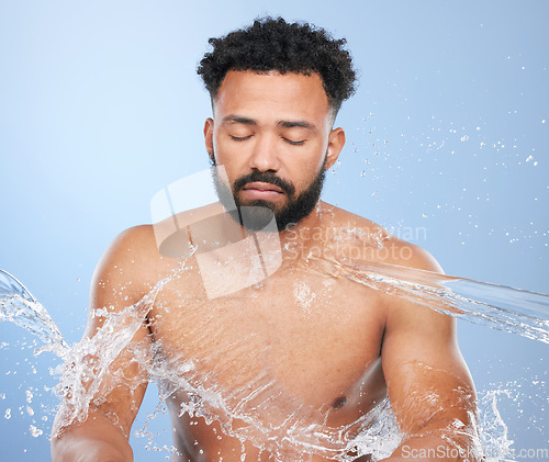 Image of Skincare, water splash and man in studio for cleaning, hygiene or cosmetic care on blue background. Shower, face and topless male model relax with luxury hydration, pamper or bathroom beauty routine