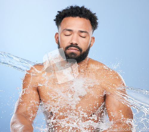 Image of Black man, water splash and skincare for hygiene, cleaning or grooming against a blue studio background. Face of African male person, model and aqua for body hydration, shower or washing skin