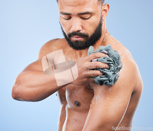 Image of Shower, washing and man with sponge in studio for cleaning, hygiene and skincare on blue background. Dermatology, bathroom and person with soap, drops and cosmetics for wellness, health or self care