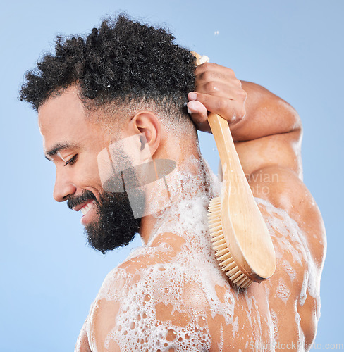 Image of Shower, brush and man in studio for back cleaning, exfoliate or wellness on blue background. Soap, cosmetics and profile of happy model with body scrubber in a bathroom for hygiene, washing or care