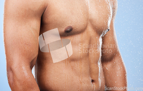 Image of Torso water drops, body shower and person wet, grooming or morning self care, maintenance or cleaning stomach. Bathroom liquid, bath or studio model hygiene, strong abdomen or wash on blue background