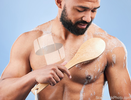 Image of Man, shower and brush for cleaning in studio with armpit, scrub and thinking for hygiene by blue background. Person, guy and foam for spa, cosmetics and wellness for body, skincare and healthy