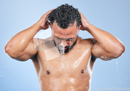 Image of Shower, washing and man with water in studio for cleaning, hygiene and skincare on blue background. Dermatology, bathroom and person with splash, drops and cosmetics for wellness, health or self care